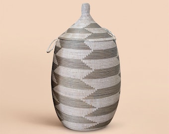 May include: A large, woven storage basket with a lid. The basket is made of natural materials and has a geometric pattern in shades of gray and white.