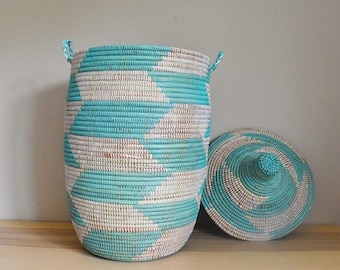 May include: A turquoise and white woven storage basket with a lid. The basket has a geometric pattern and is made of natural materials.