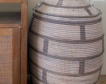 May include: A large, white and brown woven basket with a lid. The basket is made of natural materials and has a unique, hand-crafted look.
