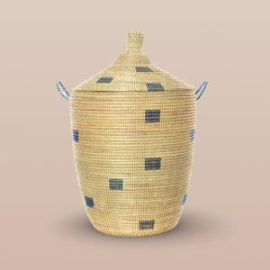 May include: A woven storage basket with a lid and handles. The basket is made of natural materials and has a geometric pattern of blue squares on a beige background.