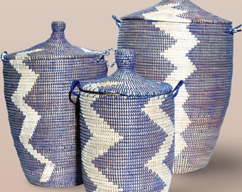 May include: Set of three blue and white woven storage baskets with lids. The baskets have a geometric pattern and are made of natural materials.