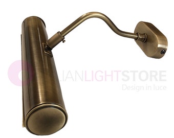 May include: A brass picture light with a curved arm and a cylindrical shade. The light is mounted on a wall.