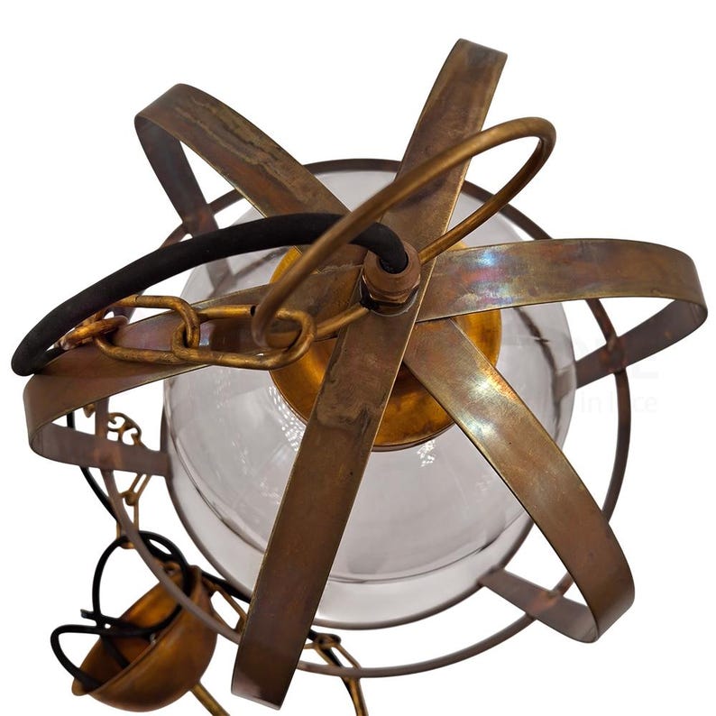 May include: A vintage-style pendant light fixture with a clear glass globe encased in a bronze-colored metal frame. The frame has a starburst design with curved metal bands. A black cord and chain are attached for hanging.