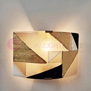 K&ouml;nnte beinhalten: Geometrische Wandleuchte in Gold, Schwarz, Wei&szlig; und Beige. Die Leuchte hat ein modernes Design mit eckigen Formen. Der Text "ITALIANLIGHTSTORE" ist auf der Seite sichtbar.
