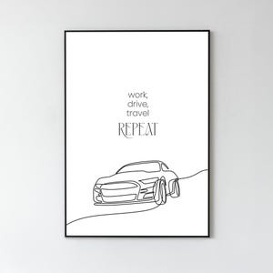 Op de afbeelding: Zwart omlijste kunstprint met een minimalistische lijntekening van een auto op een weg. De kunst bevat de woorden "work, drive, travel, repeat" in een stijlvol lettertype. Het ontwerp is eenvoudig en modern, geschikt voor thuis of op kantoor.