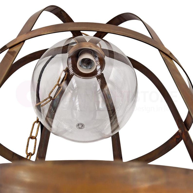 May include: A close-up of a vintage-style pendant light fixture. The fixture features a clear glass globe with a bulb socket, suspended by a brass chain. The globe is encased in a decorative, aged-bronze metal cage.