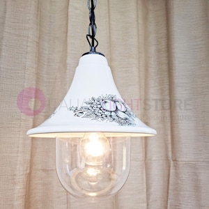 Può includere: Lampada a sospensione in ceramica bianca con catena nera e paralume in vetro trasparente. Il paralume in ceramica presenta un disegno in bianco e nero di frutta e foglie.