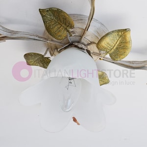 K&ouml;nnte beinhalten: Eine wei&szlig;e Deckenleuchte mit floralem Design. Die Leuchte hat f&uuml;nf Arme mit Bl&auml;ttern und einen wei&szlig;en Glasschirm in Form einer Blume.