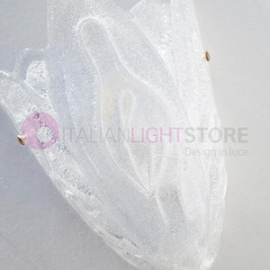 May include: A clear, textured glass wall sconce with a floral design. The sconce is mounted on a white wall and has brass-colored hardware. The text "ITALIANLIGHTSTORE Design in luce" is visible.