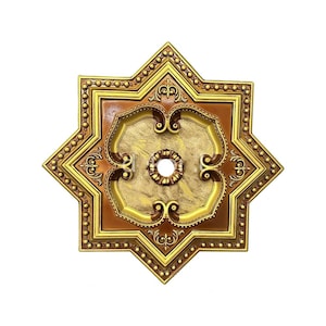May include: A star-shaped ceiling medallion featuring a central circular opening, finished in shades of metallic gold and deep bronze. The design includes intricate scrollwork, raised beaded borders, and a textured, mottled gold center panel.