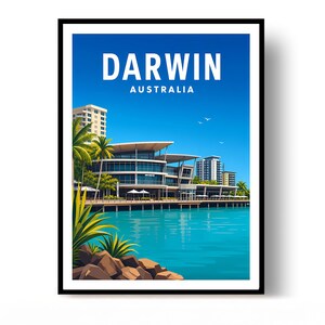 May include: A framed travel poster featuring a vibrant blue sky and turquoise water. The text DARWIN AUSTRALIA is centred at the top. The scene depicts a modern waterfront building with glass windows, palm trees, and rocky foreground elements.