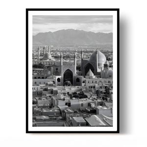 May include: A black and white framed wall art print depicting an expansive cityscape featuring large domed structures with tall minarets, flat-roofed buildings in the foreground, and a prominent mountain range visible in the distant horizon.