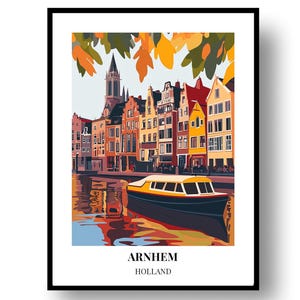Op de afbeelding: Een ingelijste kunstdruk van Arnhem, Holland. De afbeelding toont een kanaalscène met kleurrijke gebouwen, een boot en herfstbladeren. De tekst "ARNHEM HOLLAND" staat onderaan de afbeelding.