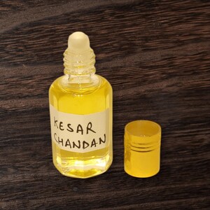 Premium Kesar Chandan attar bottle with saffron flower and sandalwood stick