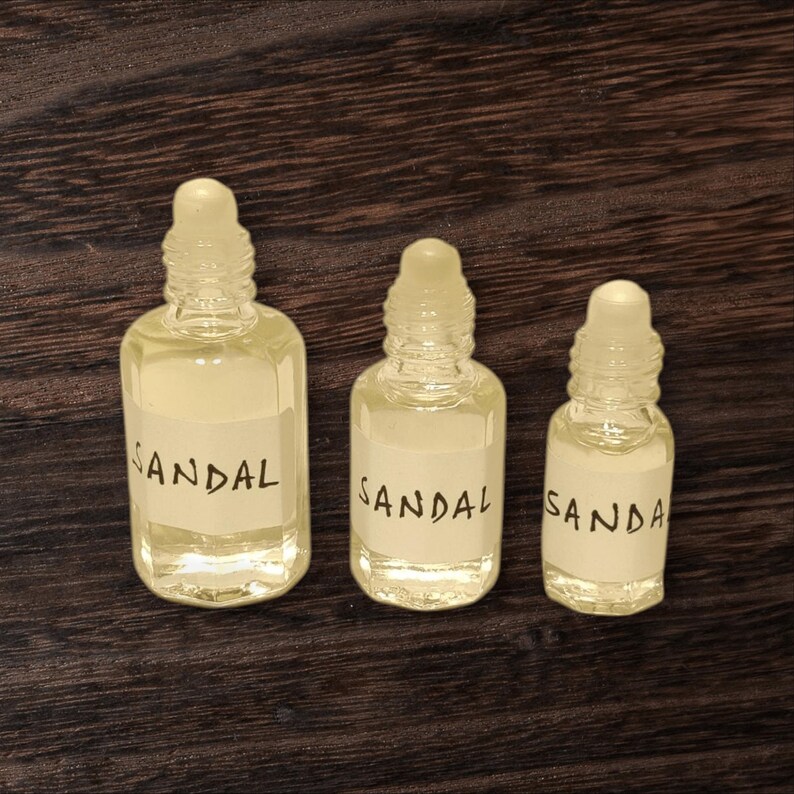 Small glass bottle of sandal attar in 3ml, 6ml, and 12ml sizes with roll-on applicator