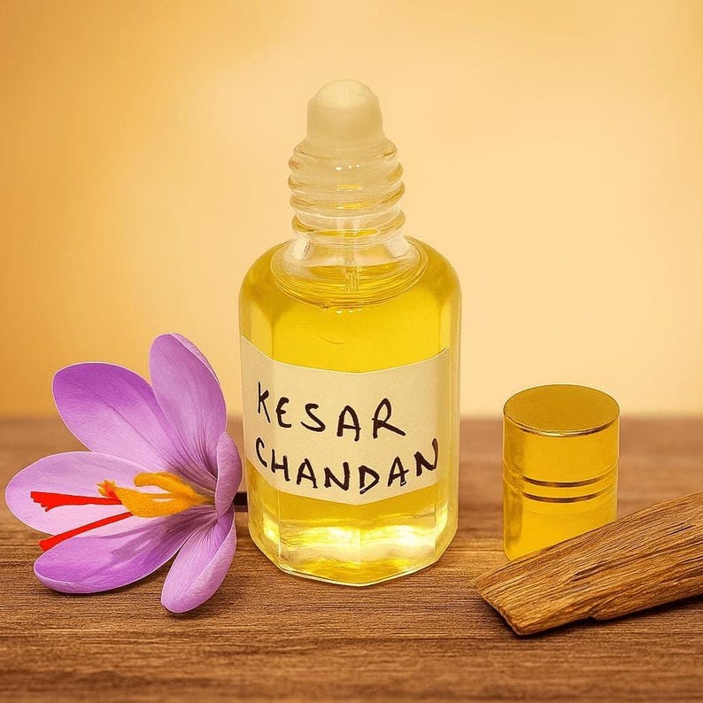 Glass bottle of Kesar Chandan attar perfume oil with saffron flower and sandalwood bark on wooden surface