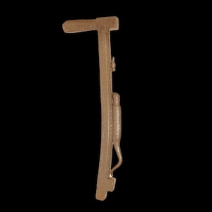 Peut inclure: Un outil en métal brun avec une longue poignée étroite et une tête en forme de T. L'outil a un petit détail décoratif sur la poignée.