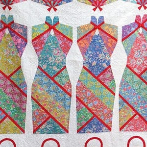 May include: A white quilt with four colorful cheongsam dresses, each made of different patterned fabrics and accented with red trim. The dresses are arranged in a row, with the top of each dress featuring a red bow.