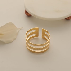 May include: A set of three ceramic mugs with a speckled, matte finish. The mugs are in shades of cream, light gray, and dark gray. Each mug has a simple, minimalist design and a rounded handle.