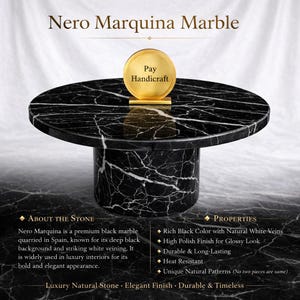 May include: A black Nero Marquina marble table with white veining. The round tabletop sits on a cylindrical base. The text "Nero Marquina Marble" is at the top. A gold-colored disc with "Pay Handicraft" is on the table.