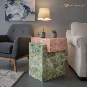 Könnte beinhalten: Ein zweistufiger Beistelltisch mit grünem und rosa Marmordesign. Oben steht eine kleine Lampe mit beigem Schirm, zusammen mit einer kleinen Tasse und einer Topf-Sukkulente. Der Text "PAY HANDICRAFT" ist sichtbar.