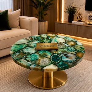 May include: A round coffee table featuring a tabletop made of polished green agate slices with varied translucent patterns. The table is supported by a central cylindrical gold-toned metal pedestal base. A small rectangular gold plaque reads Pay handicraft.