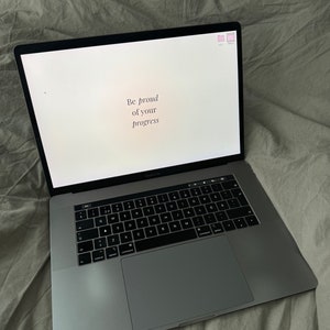 May include: A silver laptop computer with a white screen displaying the text "Be proud of your progress".