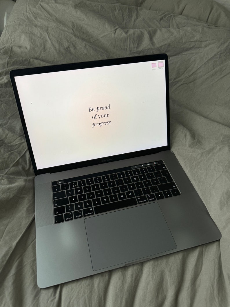 May include: A silver laptop computer with a white screen displaying the text "Be proud of your progress".