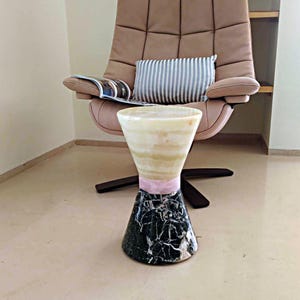 Può includere: Un tavolino da salotto in marmo con una base in marmo verde e nero, una fascia rosa e un piano in marmo bianco e giallo.