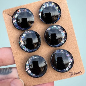 Three pairs of 20mm hand painted glittery safety eyes. They have off-set black pupils and galaxy glitter and silver stars.