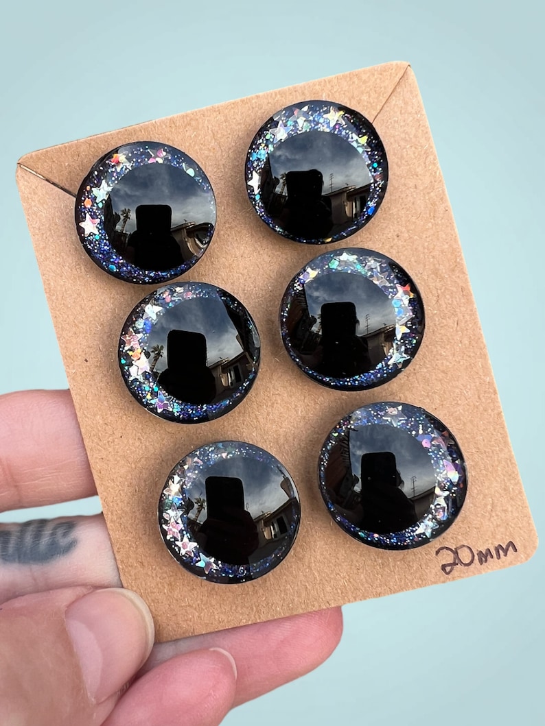 Three pairs of 20mm hand painted glittery safety eyes. They have off-set black pupils and galaxy glitter and silver stars.