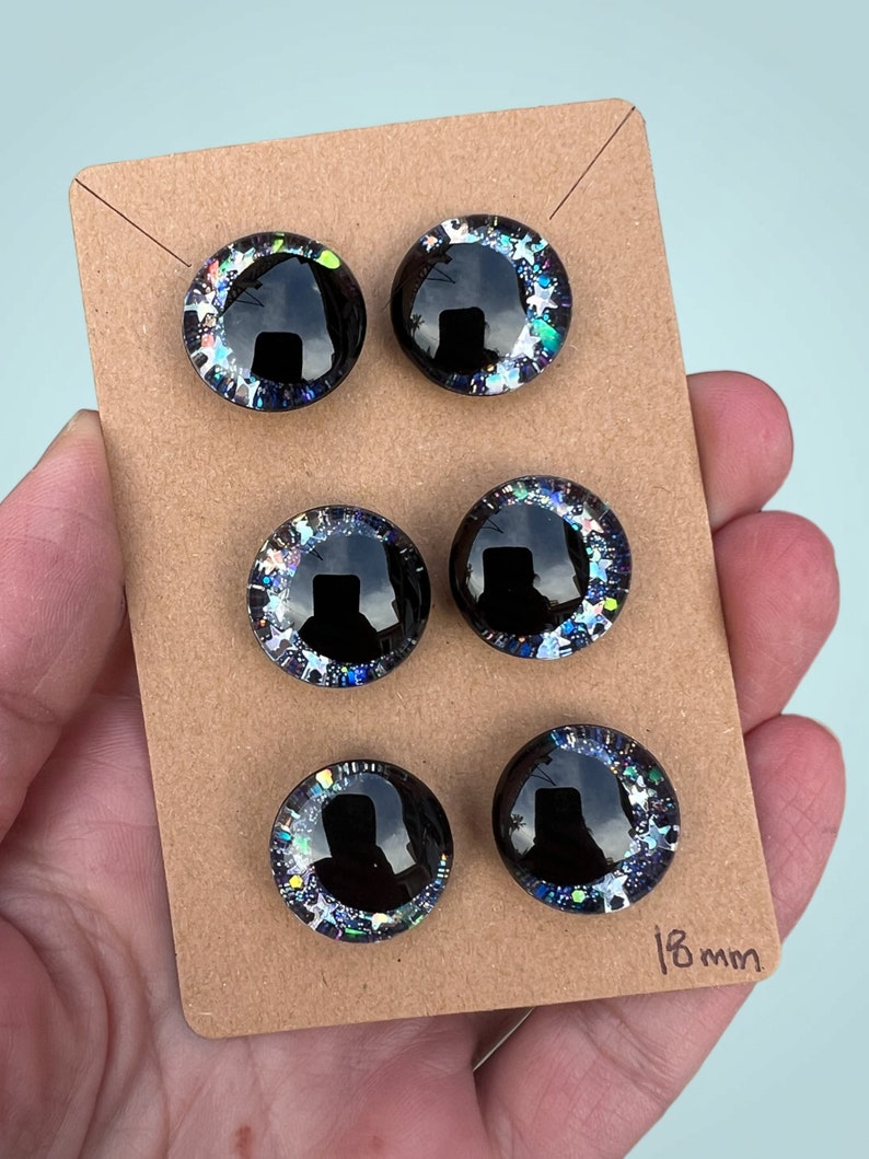 Three pairs of 18mm hand painted glittery safety eyes. They have off-set black pupils and galaxy glitter and silver stars.