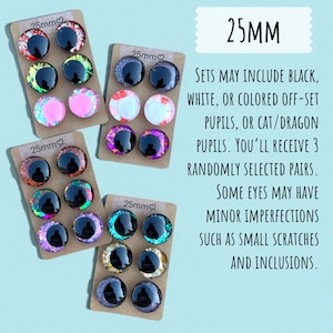 May include: Assorted 25mm craft eyes in various colors, including black, white, pink, and iridescent shades. The image shows several sets of eyes, each with three pairs, displayed on small cardboard backings. The text indicates that sets may include cat or dragon pupils.