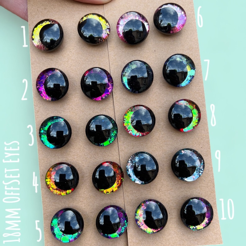 Puede incluir: Surtido de ojos de 18 mm desplazados para manualidades. Los ojos son negros con purpurina iridiscente y vienen en una variedad de colores, incluyendo rosa, verde, azul y morado. Los ojos est&aacute;n numerados del 1 al 10.