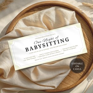 May include: A light cream-colored babysitting voucher with the text "One Night of Babysitting" in a decorative font. The voucher is on a wooden tray with a cream-colored cloth and dried plants. The text "Editable on Canva" is also visible.