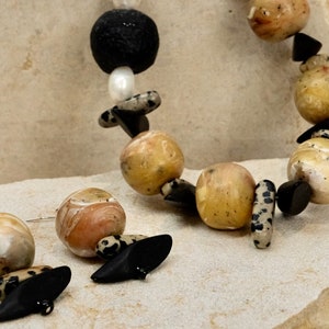 May include: A necklace and earrings set featuring large, round, yellow and white beads with black accents. The beads have a marbled appearance.