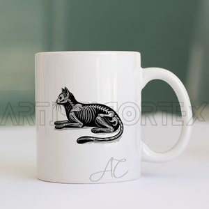 Puede incluir: Taza de cer&aacute;mica blanca con una ilustraci&oacute;n en blanco y negro de un esqueleto de gato. La taza tiene una inscripci&oacute;n en negro que dice "AC".
