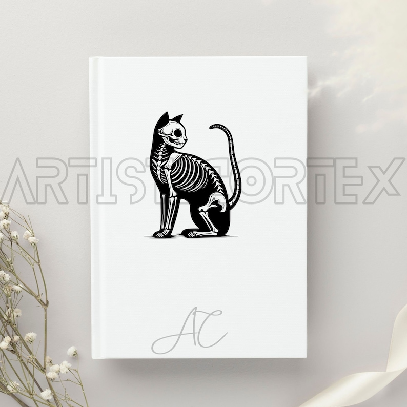 Puede incluir: Un cuaderno blanco con una ilustraci&oacute;n en blanco y negro de un esqueleto de gato. El cuaderno tiene la letra "A" escrita en gris en la parte delantera.