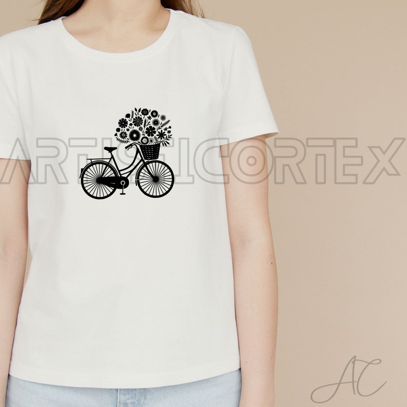 Puede incluir: Una camiseta blanca con una silueta negra de una bicicleta con una cesta llena de flores.