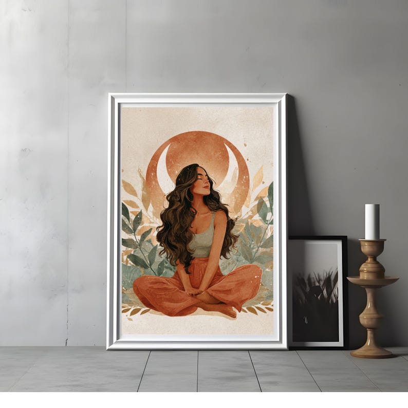 May include: A framed art print featuring a woman in a meditative pose. The artwork showcases a woman with long brown hair, wearing a light green top and orange pants, set against a backdrop of a crescent moon and foliage. The frame is white.