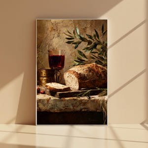 Puede incluir: Pintura de naturaleza muerta con una hogaza de pan, una copa de vino tinto y un pequeño recipiente de latón. Una rebanada de pan descansa sobre una tabla de cortar de madera. Ramas de olivo añaden un elemento natural. El fondo tiene un aspecto texturizado y envejecido.