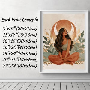 May include: Framed art print featuring a woman in a meditative pose, with long brown hair and wearing a light green top and orange pants. The background includes a crescent moon and foliage. The text on the left indicates available print sizes.