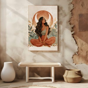 May include: A framed art print depicts a woman in a meditative pose, seated with legs crossed. She wears a teal top and rust-colored pants. The background features a crescent moon and foliage, with a neutral color palette.