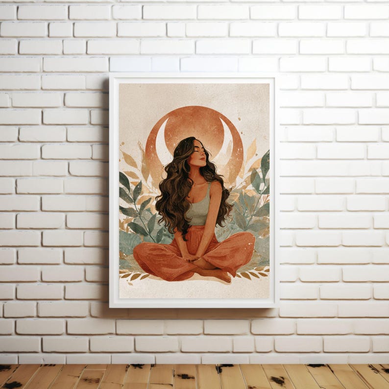 May include: A framed art print featuring a woman in a meditative pose. She is wearing a light green top and orange pants, with long, flowing brown hair. The background includes a crescent moon and foliage in shades of orange, green, and beige.