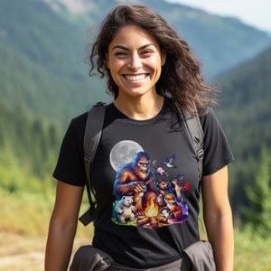 May include: A black t-shirt with a graphic of a Bigfoot roasting marshmallows around a campfire with other woodland creatures. The graphic is colorful and features a full moon in the background.