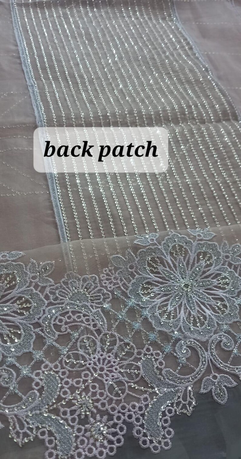 May include: A close-up of a sheer fabric with a silver glitter pattern. The fabric has a delicate lace trim with a floral design. The text "back patch" is visible in the image.
