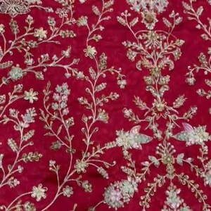 May include: Red fabric with a floral embroidery design. The embroidery is in silver and white thread with small pearl-like beads.
