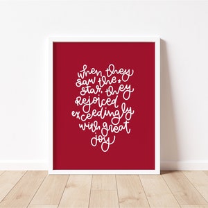 May include: A red square print with white text that reads "When they saw the star, they rejoiced exceedingly with great joy."