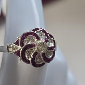 Anel moderno em estilo neo art déco com diamantes e rubis em formato de flor, assinado por designer.
