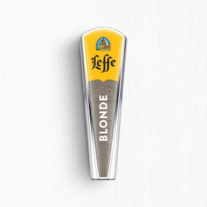 May include: A tapered Leffe beer tap handle featuring a yellow top section with a stained glass window logo and the black Leffe brand name. The lower section is grey with the word BLONDE printed vertically in white, accented by silver trim.